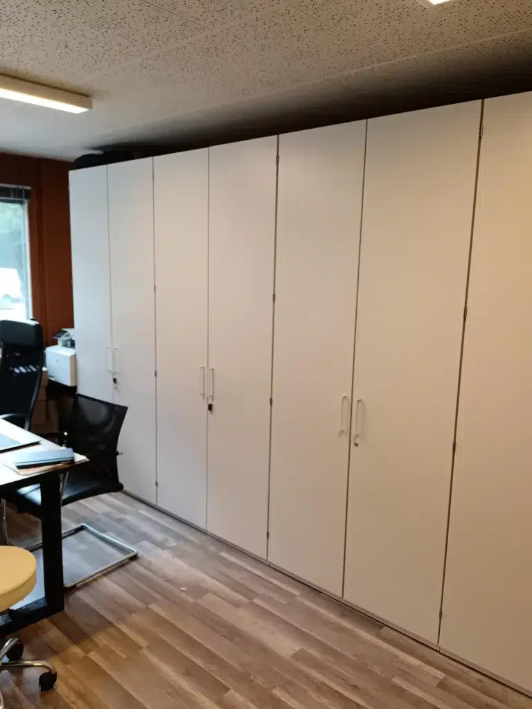 Armoire de bureau en bois. Rangée d'armoire au fond de la pièce, derrière le bureau.